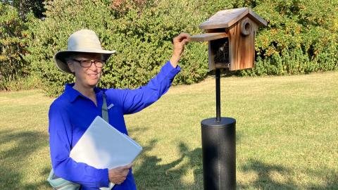 Docent Janet James stands with a bird house